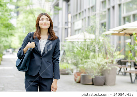 A businesswoman walks through a lush, green office district. A businesswoman walks through a lush, green office district. 140843432