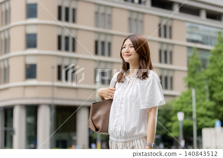 A smiling Japanese woman walking through an office district. A smiling Japanese woman walking through an office district. 140843512