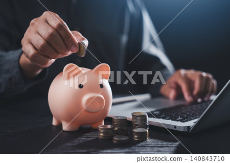 Man puts coin for investment money into piggy bank for finance wealth, to save cash or currency deposit while using laptop computer for economy account accounting and future growth Man puts coin for investment money into piggy bank for finance wealth, to save cash or currency deposit while using laptop computer for economy account accounting and future growth 140843710