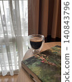 Morning Espresso in Double Wall Glass Next to Book by Window 140843796
