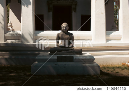 Meditating Buddha Statue Before a Traditional Thai Temple in Ayutthaya 140844230