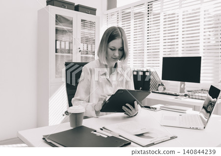 Young businesswoman smiling as she works on a laptop sitting in an modern office 140844239