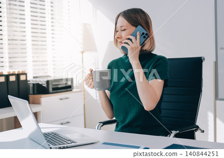 Happy female entrepreneur using smart phone in office. 140844251