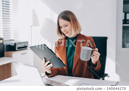 Woman smiling to herself as she works in an office Woman smiling to herself as she works in an office 140844278