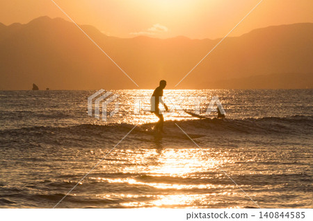 Shonan Kugenuma Beach: Sunset with a pollen halo and the silhouettes of surfers. Shonan Kugenuma Beach: Sunset with a pollen halo and the silhouettes of surfers. 140844585