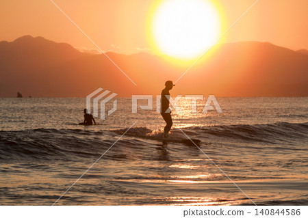 Shonan Kugenuma Beach: Sunset with a pollen halo and the silhouettes of surfers. Shonan Kugenuma Beach: Sunset with a pollen halo and the silhouettes of surfers. 140844586