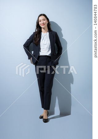 A smiling businesswoman in a suit stands confidently against a light blue background, symbolizing career advancement, job changes, and recruitment. A smiling businesswoman in a suit stands confidently against a light blue background, symbolizing career advancement, job changes, and recruitment. 140844783