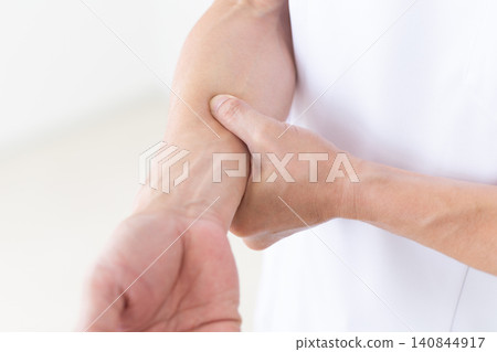 一位身穿白大褂的中年男性針灸師/整骨師正在按壓手臂上的穴位。 140844917