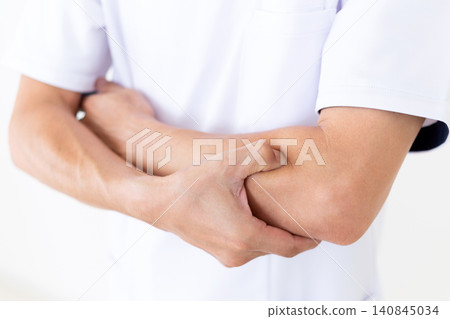 A middle-aged male acupuncturist/osteopath in a white coat pressing on pressure points on the arm. A middle-aged male acupuncturist/osteopath in a white coat pressing on pressure points on the arm. 140845034