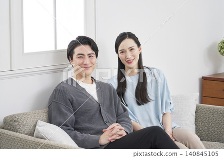 Portrait of a middle-aged couple in their living room, looking directly at the camera. Portrait of a middle-aged couple in their living room, looking directly at the camera. 140845105