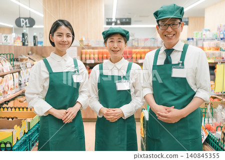 Three staff members lined up in a supermarket Three staff members lined up in a supermarket 140845355