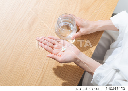 A woman taking medication. Pharmaceuticals, supplements, over-the-counter medicines, generics. A woman taking medication. Pharmaceuticals, supplements, over-the-counter medicines, generics. 140845450