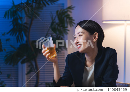 A woman drinking alcohol in a dark room. Beer, whiskey, drinking party, izakaya, bar, snack bar, drinking at home 140845469