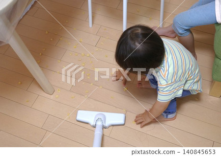 A scene of cleaning up food spilled on the floor by a child. A scene of cleaning up food spilled on the floor by a child. 140845653