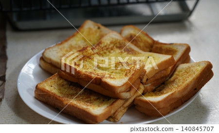 Golden Garlic Bread Stacked on a White Plate 140845707