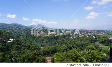 Lush Green Landscape with Buildings and Distant Mountains Lush Green Landscape with Buildings and Distant Mountains 140845847
