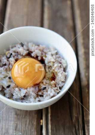 Rice with a raw egg on top of sixteen-grain rice with a drizzle of soy sauce. 140846408