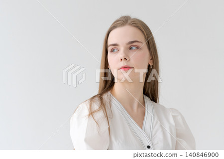 Serene Young Woman with Natural Makeup in a White Dress Portrait 140846900