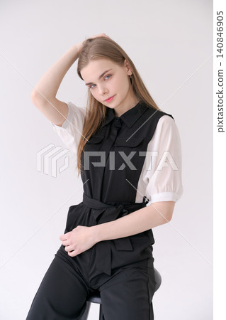 Relaxed Young Woman Sitting on a Stool in a Black Jumpsuit Lifestyle Relaxed Young Woman Sitting on a Stool in a Black Jumpsuit Lifestyle 140846905