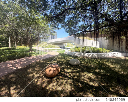 Modern park architecture with banyan tree and winding pathways under sunlight Modern park architecture with banyan tree and winding pathways under sunlight 140846969