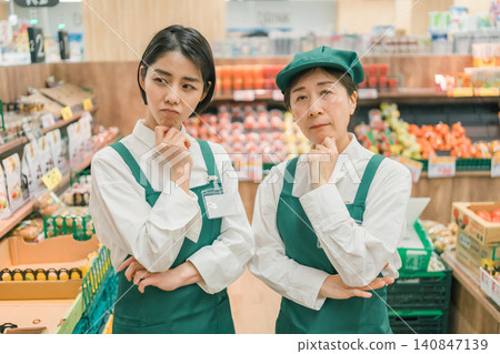 兩名女店員雙手交叉在胸前,陷入沉思。 兩名女店員雙手交叉在胸前,陷入沉思。 140847139
