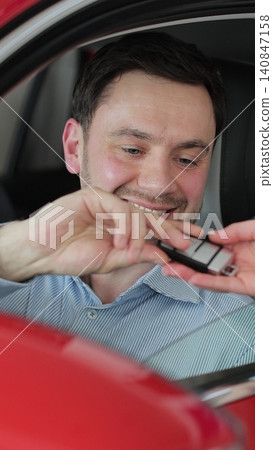 Vertical video Happy young man in the car getting the keys from the dealer. Concept of car shopping, buying, and dealership. Vertical video Happy young man in the car getting the keys from the dealer. Concept of car shopping, buying, and dealership. 140847158