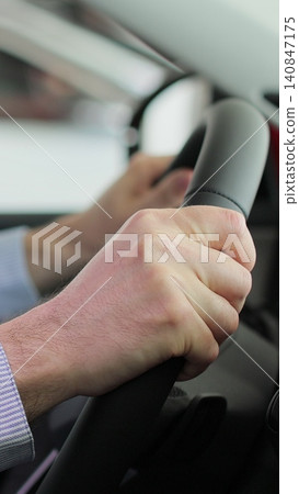 Vertical video Close up young man auto driver car owner holding steering wheel buy new automobile dealership inside vehicle. Concept of car shopping, buying, and dealership. Vertical video Close up young man auto driver car owner holding steering wheel buy new automobile dealership inside vehicle. Concept of car shopping, buying, and dealership. 140847175