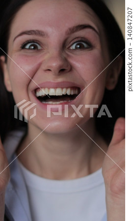Vertical video Young woman demonstrates expresses a range of positive emotions, showcasing surprise and happiness, raising her hands. Vertical video Young woman demonstrates expresses a range of positive emotions, showcasing surprise and happiness, raising her hands. 140847207