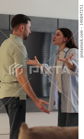 Vertical video Man and woman in discussion, showing emotions of stress in a cozy living room setting. Vertical video Man and woman in discussion, showing emotions of stress in a cozy living room setting. 140847251