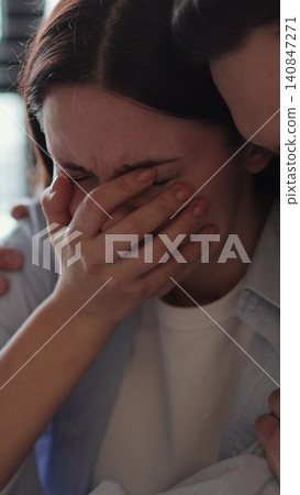 Vertical video Young woman sitting on sofa, looks pessimistic and sad, almost crying, man calming her down, softly touches and hugs her. Partnership and support concept. Vertical video Young woman sitting on sofa, looks pessimistic and sad, almost crying, man calming her down, softly touches and hugs her. Partnership and support concept. 140847271