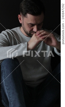 Vertical video Sad man sitting in the dark leaning against the wall in home. Family problems, stress. Vertical video Sad man sitting in the dark leaning against the wall in home. Family problems, stress. 140847292