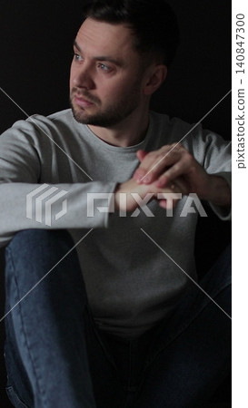 Vertical video Sad man sitting in the dark leaning against the wall in home. Family problems, stress. 140847300