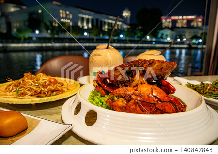 Delicious Singapore chili crab served with fresh coconuts at a riverside restaurant overlooking the illuminated city skyline during night time Delicious Singapore chili crab served with fresh coconuts at a riverside restaurant overlooking the illuminated city skyline during night time 140847843