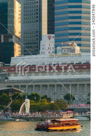 SINGAPORE - JUNE 30, 2025: Tourists visit Merlion Park near the Fullerton Hotel along the Singapore River waterfront at sunset SINGAPORE - JUNE 30, 2025: Tourists visit Merlion Park near the Fullerton Hotel along the Singapore River waterfront at sunset 140847846