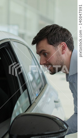 Vertical video Man buyer choosing examine dreaming male auto showroom touch new car. Concept of car shopping, buying, and dealership. Vertical video Man buyer choosing examine dreaming male auto showroom touch new car. Concept of car shopping, buying, and dealership. 140847891