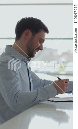 Vertical video Handsome man buying a new car and signing the contract, car in the background. Saleswoman gives a car keys to buyer. Concept of car shopping, buying, and dealership. Vertical video Handsome man buying a new car and signing the contract, car in the background. Saleswoman gives a car keys to buyer. Concept of car shopping, buying, and dealership. 140847915