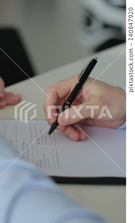 Vertical video Close up of man buying a car and signing the contract, car in the background. Concept of car shopping, buying, and dealership. Vertical video Close up of man buying a car and signing the contract, car in the background. Concept of car shopping, buying, and dealership. 140847920