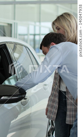 Vertical video Young couple discussing chosen auto in automobile showroom. Concept of car shopping, buying, and dealership. 140847938