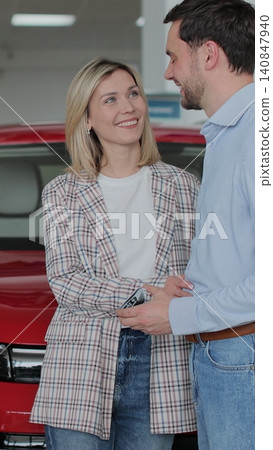 Vertical video Young couple buying new car in car dealership. Saleswoman giving car keys to new car happy couple family buyers. Auto business concept. Vertical video Young couple buying new car in car dealership. Saleswoman giving car keys to new car happy couple family buyers. Auto business concept. 140847940