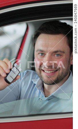 Vertical video Young man showing key to new car. Man holding car keys at the dealership salon. Auto business concept. Vertical video Young man showing key to new car. Man holding car keys at the dealership salon. Auto business concept. 140847989