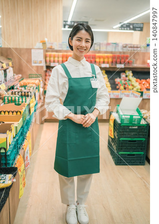 A female store clerk smiles in the aisle of the supermarket. A female store clerk smiles in the aisle of the supermarket. 140847997