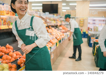 超市水果區,一名女店員大聲笑著。 超市水果區,一名女店員大聲笑著。 140848279