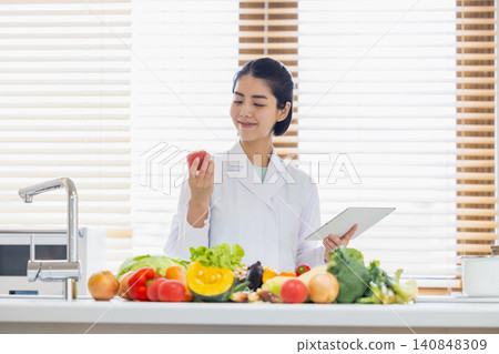 Registered dietitian: A dietitian looking at a tablet in front of a large pile of vegetables. Registered dietitian: A dietitian looking at a tablet in front of a large pile of vegetables. 140848309
