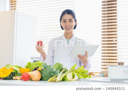 Registered dietitian: A dietitian looking at a tablet in front of a large pile of vegetables. Registered dietitian: A dietitian looking at a tablet in front of a large pile of vegetables. 140848311
