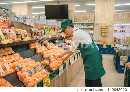 A male store clerk is stocking the shelves in the mandarin orange section of a supermarket. A male store clerk is stocking the shelves in the mandarin orange section of a supermarket. 140848610
