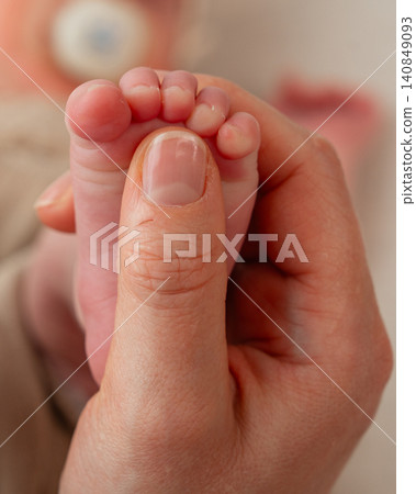 Vertical macro shot of a mother holding her newborn baby's tiny foot securely in her hand. Focus on the soft skin texture and small toes. Perfect for maternal health and parenting media. A peaceful Vertical macro shot of a mother holding her newborn baby's tiny foot securely in her hand. Focus on the soft skin texture and small toes. Perfect for maternal health and parenting media. A peaceful 140849093
