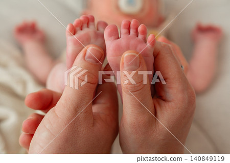 A wide landscape lifestyle photo of a mother gently cradling her newborn baby's tiny feet in her hands. Soft bokeh background with the babys face slightly visible. Warm and emotional tone. Beautiful A wide landscape lifestyle photo of a mother gently cradling her newborn baby's tiny feet in her hands. Soft bokeh background with the babys face slightly visible. Warm and emotional tone. Beautiful 140849119