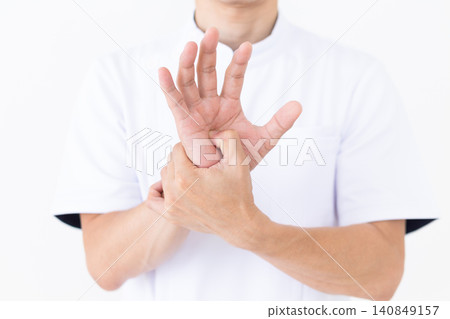 A middle-aged male acupuncturist/osteopath in a white coat pressing on pressure points (Teshin) in the palm of the hand. A middle-aged male acupuncturist/osteopath in a white coat pressing on pressure points (Teshin) in the palm of the hand. 140849157