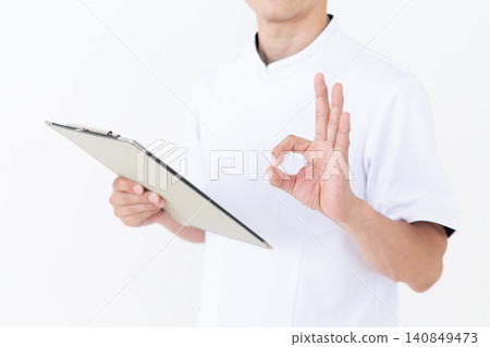 A middle-aged male acupuncturist/osteopath in a white coat, holding a binder and making a circular pose. A middle-aged male acupuncturist/osteopath in a white coat, holding a binder and making a circular pose. 140849473