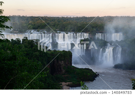 Breathtaking iguazu falls cascade down lush green cliff creating peaceful mist Breathtaking iguazu falls cascade down lush green cliff creating peaceful mist 140849783